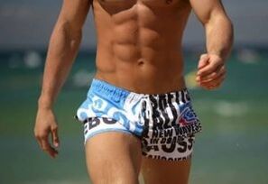 man in swimming trunks increasing the penis gel